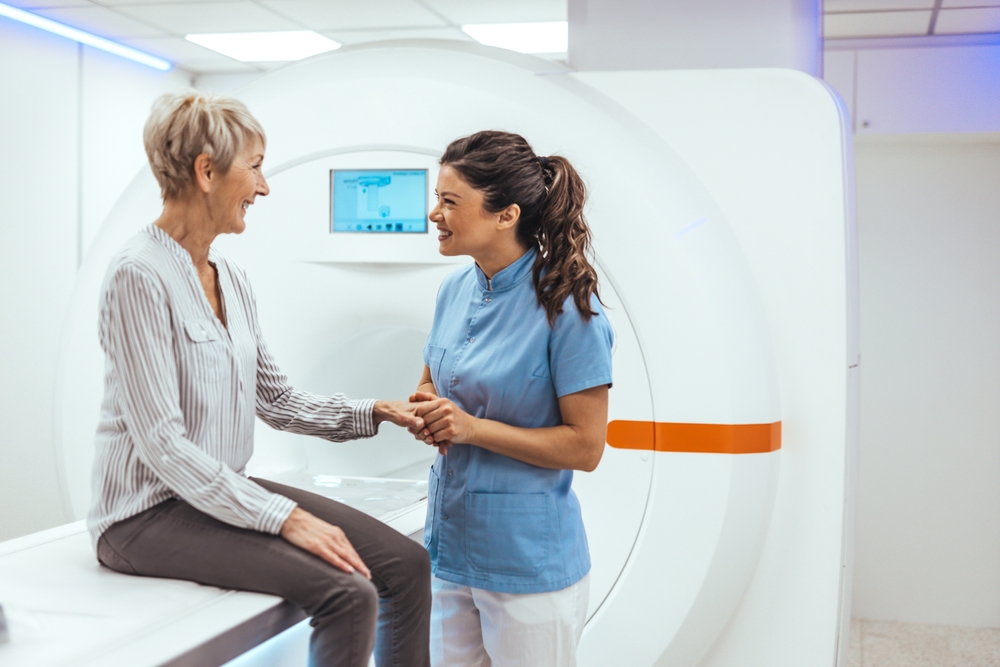 What to Expect at a Full-Body MRI Screening: A Step-by-Step Guide 1 Healthcare professional in blue scrubs shakes hands with a smiling patient beside an MRI scanner for reassurance and care