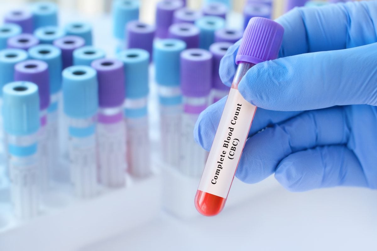 A gloved hand holds a labeled Complete Blood Count tube among other sample tubes.